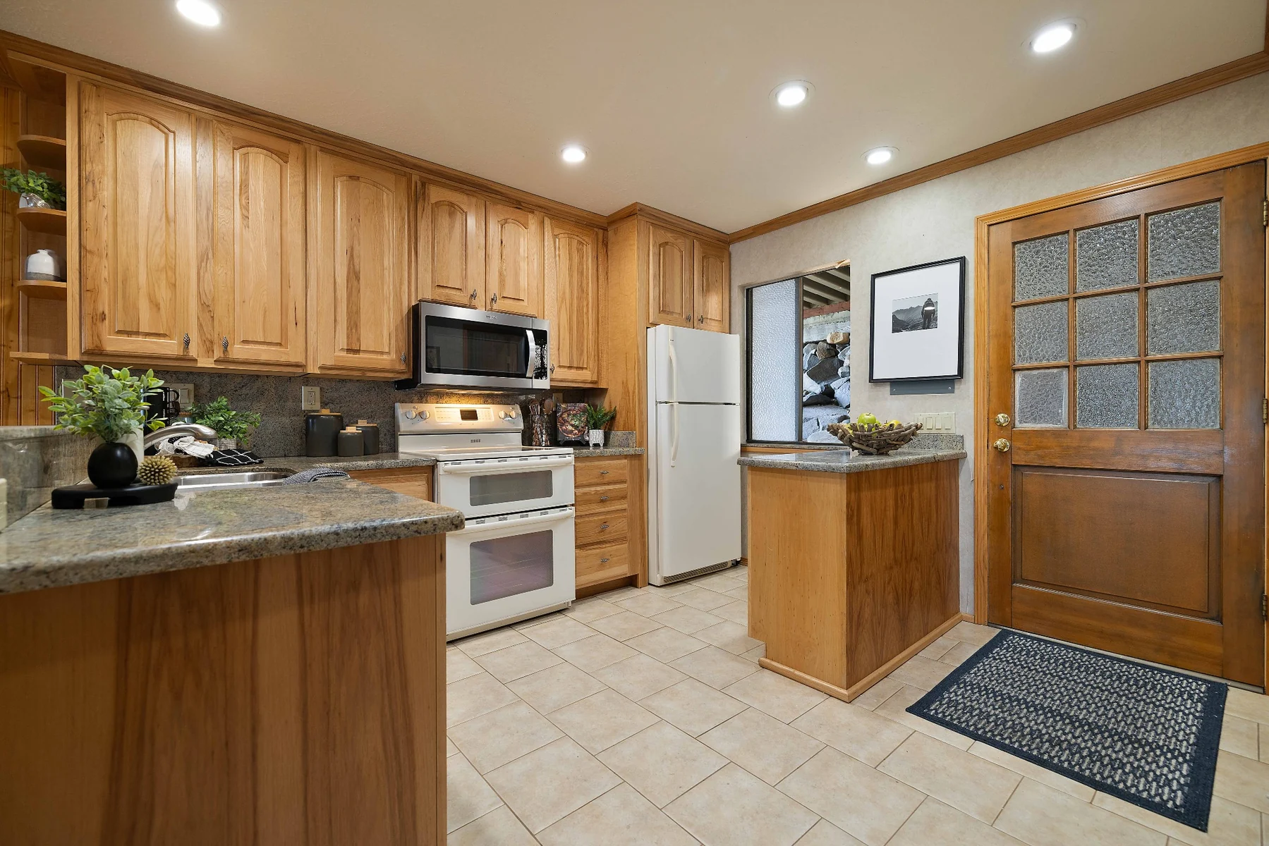 Kitchen entry with wood cabinetry, tile flooring and glass-paneled door